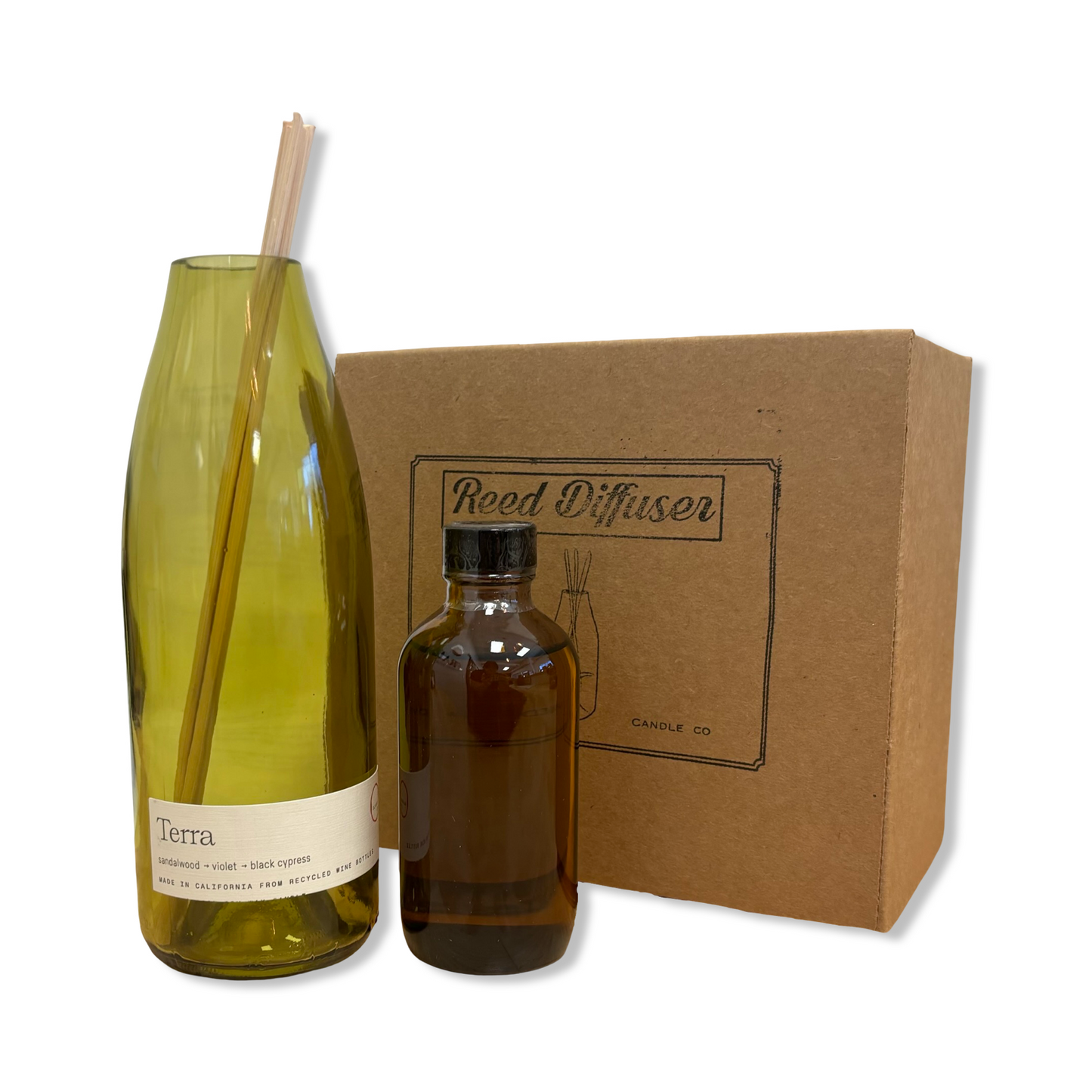 Reed diffuser set with a green bottle, brown bottle, and cardboard box on a white background